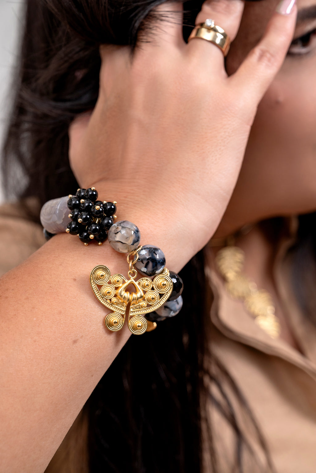Frau trägt exotisches grau-schwarzes Edelsteinarmband mit 24K Gold Anhänger 